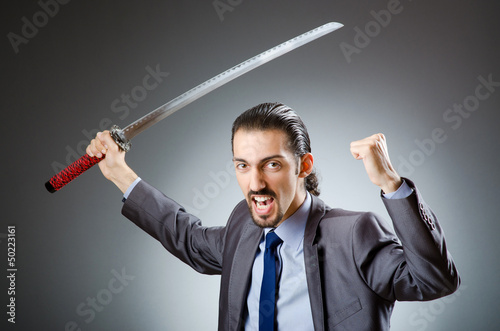 Photo: Angry businessman with sword in dark room Angry businessman with sword in dark room