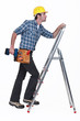 Carpenter with drill climbing step-ladder