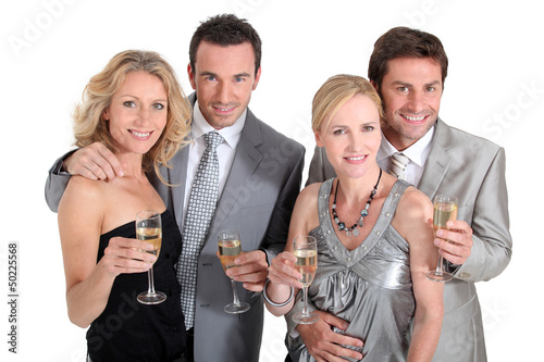 Photo: Double date: couples in party dress drinking champagne Double date: couples in party dress drinking champagne