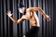 Muscular actor with mask against curtain