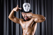 Muscular actor with mask against curtain