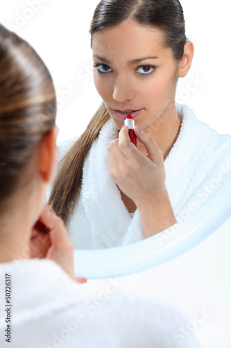 Photo: Young woman applying red lipstick Young woman applying red lipstick