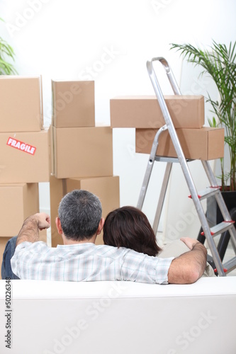 Photo: Couple sat on sofa in new house Couple sat on sofa in new house