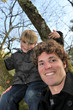 Little boy climbing tree with father