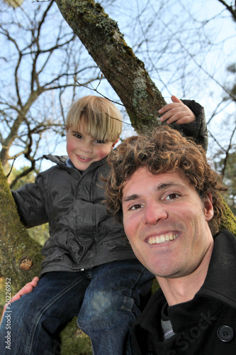 Photo: Little boy climbing tree with father Little boy climbing tree with father