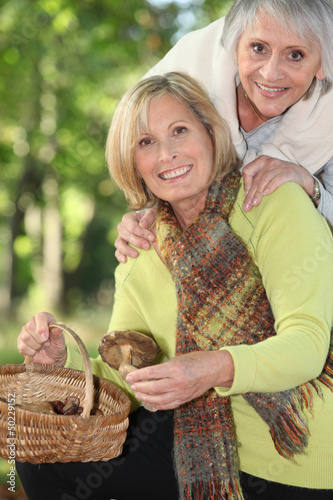 Photo: two seniors women gathering chestnuts two seniors women gathering chestnuts