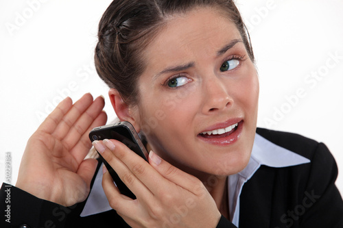 Photo: young businesswoman straining her ears with cell phone young businesswoman straining her ears with cell phone