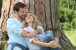 Happy couple sat by tree