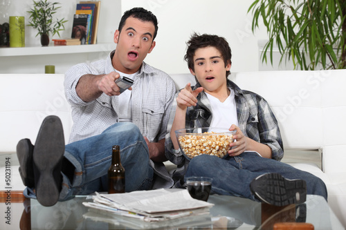 Photo: Father and son watching television together Father and son watching television together