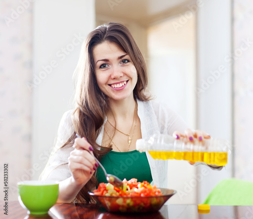 Photo: Woman pouring vegetable oil salad Woman pouring vegetable oil salad