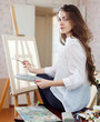 Long-haired woman with oil colors near easel