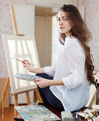 Photo: Long-haired woman with oil colors near easel Long-haired woman with oil colors near easel