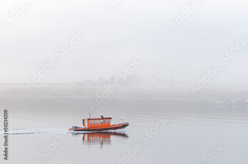 Photo: Smale lone orange boat sailing in mist Smale lone orange boat sailing in mist