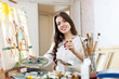 Happy young woman paints   on canvas