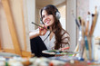 Long-haired  artist  in headphones paints picture