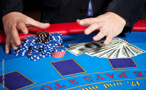Photo: men's hand with chips, cards and dollars banknotes on table men's hand with chips, cards and dollars banknotes on table
