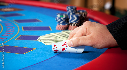 Photo: men's hand with chips, cards and dollars banknotes on table men's hand with chips, cards and dollars banknotes on table