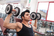 Photo: Young man exercising with dumbbells in a gym. Young man exercising with dumbbells in a gym.
