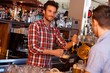 Bartender serving draught beer in bar