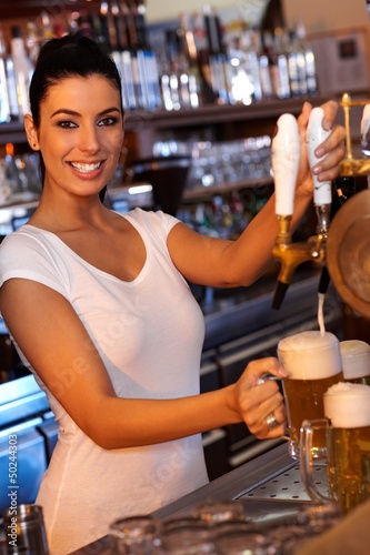 Photo: Attractive bartender tapping beer in bar Attractive bartender tapping beer in bar