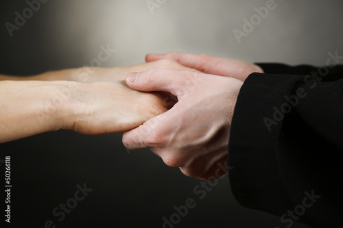 Photo: Priest holding woman hands, on black background Priest holding woman hands, on black background