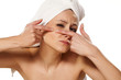 Scowling girl squeezes her acne with a towel on her head