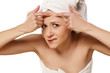 Photo: Scowling girl squeezes her acne with a towel on her head Scowling girl squeezes her acne with a towel on her head