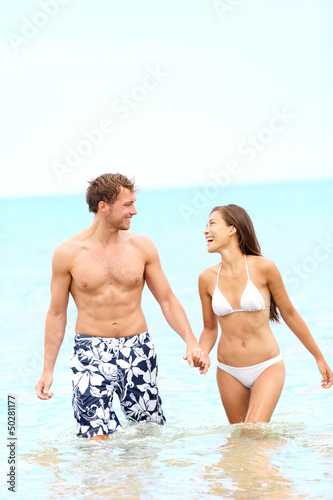 Photo: Couple on beach walking in water Couple on beach walking in water