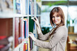 young student selecting book in library