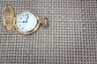 Antique pocket watch on a textured burlap. Close-up.