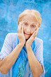 Foto: Portrait of surprised senior woman with hands on face on blue ba Portrait of surprised senior woman with hands on face on blue ba