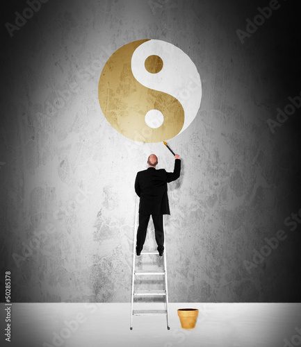 Photo: Work life balance concept - man painting golden yin-yang symbol Work life balance concept - man painting golden yin-yang symbol