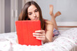 Young woman using tablet computer in bed