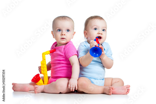 Photo: Funny babies girl and boy playing musical toys. Isolated on whi Funny babies girl and boy playing musical toys. Isolated on whi