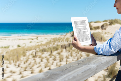Photo: frau liest ein ebook am strand frau liest ein ebook am strand