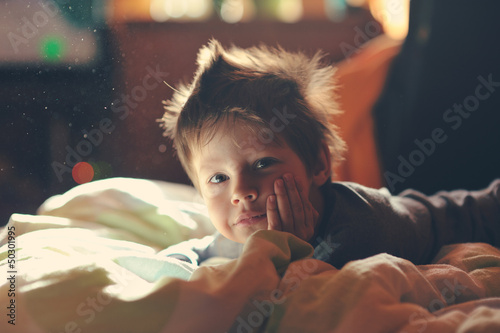 Photo: child from sleep lying on the sofa and enjoying life child from sleep lying on the sofa and enjoying life