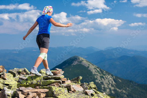 Photo: Athlet looking girl with bandage on knees jumps over stones in C Athlet looking girl with bandage on knees jumps over stones in C
