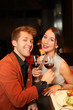 Happy man and woman with a glass of wine watching the camera
