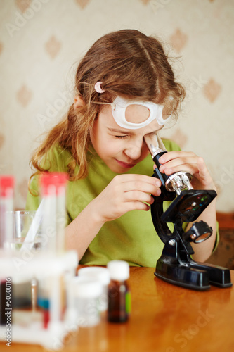 Photo: Girl in green t-shirt attentively looks into microscope Girl in green t-shirt attentively looks into microscope