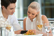 Cute couple looking at smart phone at dinner.