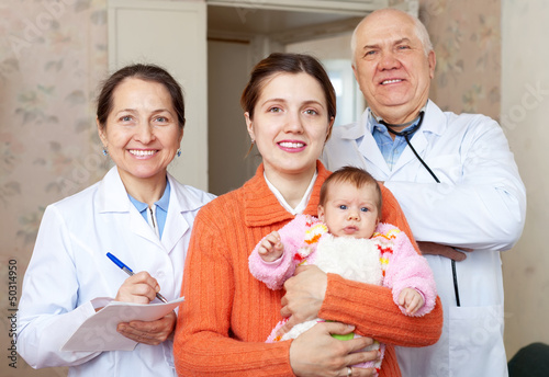 Photo: Portrait of two doctors and woman holding baby Portrait of two doctors and woman holding baby