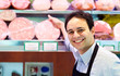 Shopkeeper showing mortadella in an italian grocery store
