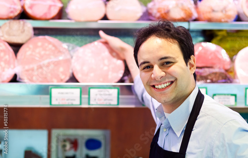 Photo: Shopkeeper showing mortadella in an italian grocery store Shopkeeper showing mortadella in an italian grocery store