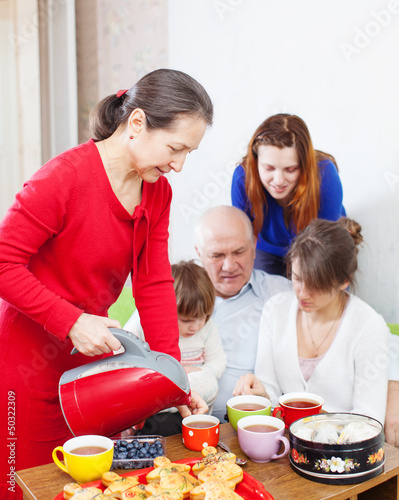 Photo: woman in red pours tea for family woman in red pours tea for family
