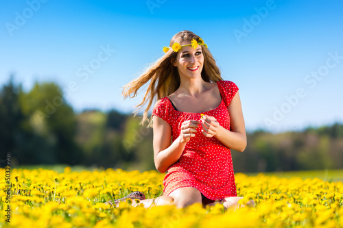 Photo: Girl in spring on a flower meadow with dandelion Girl in spring on a flower meadow with dandelion