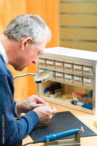 Photo: Akustiker arbeitet an einem Hörgerät Akustiker arbeitet an einem Hörgerät
