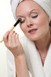 Beautiful danish caucasian woman doing her makeup in white