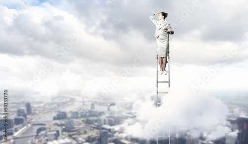 Photo: Businesswoman standing on ladder Businesswoman standing on ladder