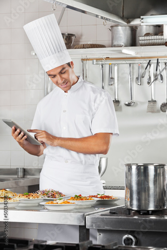 Photo: Chef Using Tablet With Pasta Dishes At Counter Chef Using Tablet With Pasta Dishes At Counter