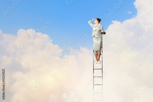 Photo: Businesswoman standing on ladder Businesswoman standing on ladder